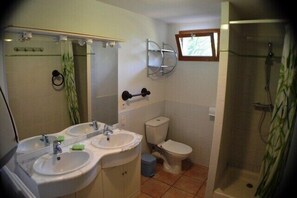 Une salle de bain avec deux lavabos, des toilettes et une douche.