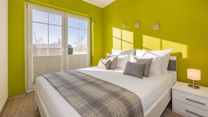 A bedroom with a bed, bedside table, and a window with blinds. - Apartment Kleine Auszeit 02 - cozy domicile in the center of Koserow (Koserow)