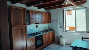 A kitchen with wooden cabinets, a gas stove, and a window with a view. - Is Araus Holiday apartment for 4 people 50 meters from the sea in Mandriola (Mandriola)