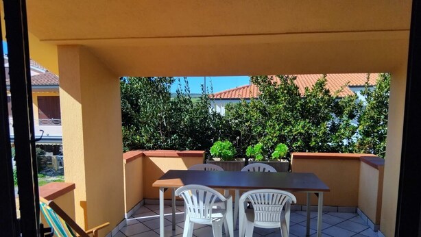 A balcony with a table and two white chairs, a striped beach chair, and potted plants. - Is Araus Holiday apartment for 4 people 50 meters from the sea in Mandriola (Mandriola)