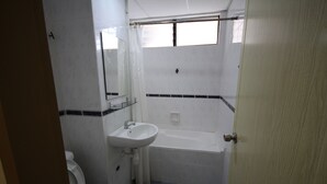 A small, compact bathroom with a toilet, sink, and bathtub. - Seaview Condo with Pool (Batu Ferringhi)