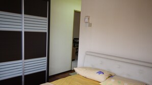 A bedroom with a bed, a wardrobe, and a wall-mounted thermostat. - Seaview Condo with Pool (Batu Ferringhi)