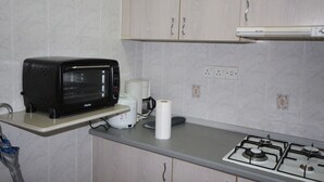 A kitchen with a microwave, coffee maker, and gas stove. - Seaview Condo with Pool (Batu Ferringhi)