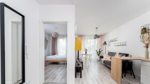 A modern apartment with a large mirror, a bed, a dining area, and a kitchen. - Malila Apartments Konopnickiej 63E (Kraków)