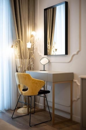 Una habitación con escritorio, silla, espejo y lámpara.