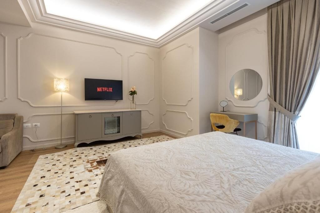 A hotel room with a bed, a TV mounted on the wall, a desk, and a chair.