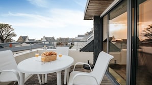 A rooftop terrace with a round table, white chairs, and a basket of bread and drinks. - Seaview Duplex with Terrace in Le Conquet (Le Conquet)