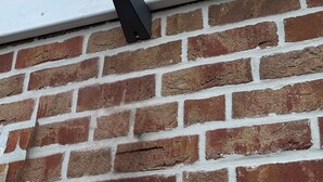 Una canal metàl·lica adossada a una paret de maó amb un sostre metàl·lic a sobre.