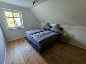 A bedroom with a bed, a nightstand, a lamp, and a window. - 53° North Vacation Home - New Construction 2026 (Hinte)