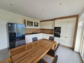A modern kitchen with a wooden dining table, white cabinets, and a black refrigerator. - 53° North Vacation Home - New Construction 2026 (Hinte)