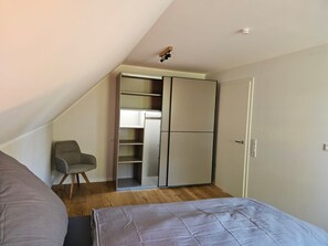 Ein Schlafzimmer mit Bett, Stuhl, Kleiderschrank und Deckenleuchte.
