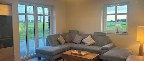 A modern living room with a sectional sofa, a wooden coffee table, and a lamp.