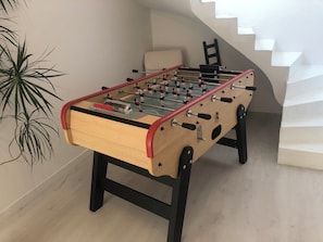 A foosball table in a room with a staircase and a plant. - MAGNIFICENT HOUSE WITH SEA VIEW (L'HOPITAL CAMFROUT)