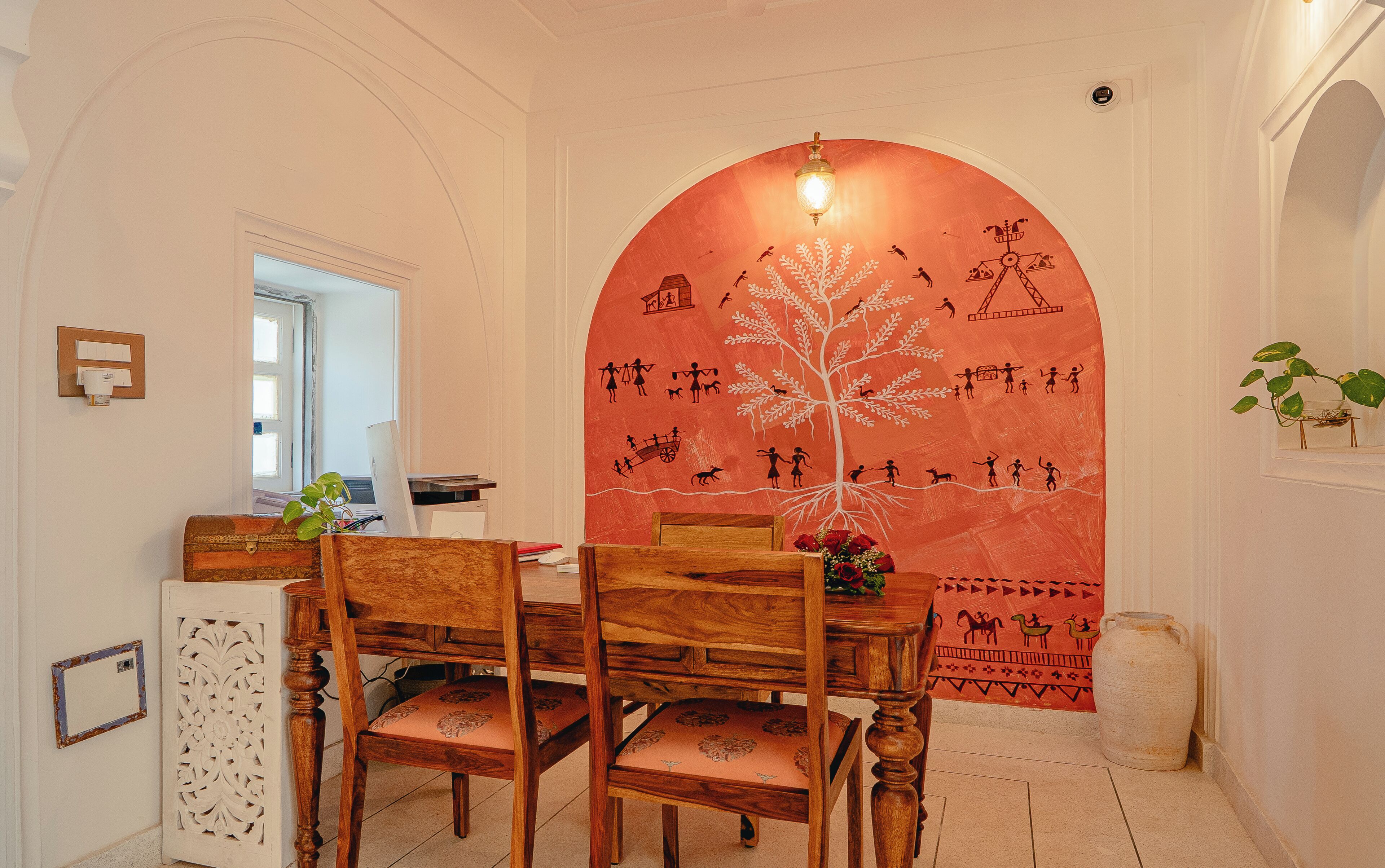 A dining area with a wooden table and chairs, a wall with a mural, and a window with a view.
