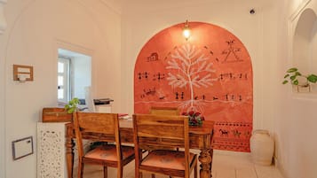 A dining area with a wooden table and chairs, a wall with a mural, and a window with a view.