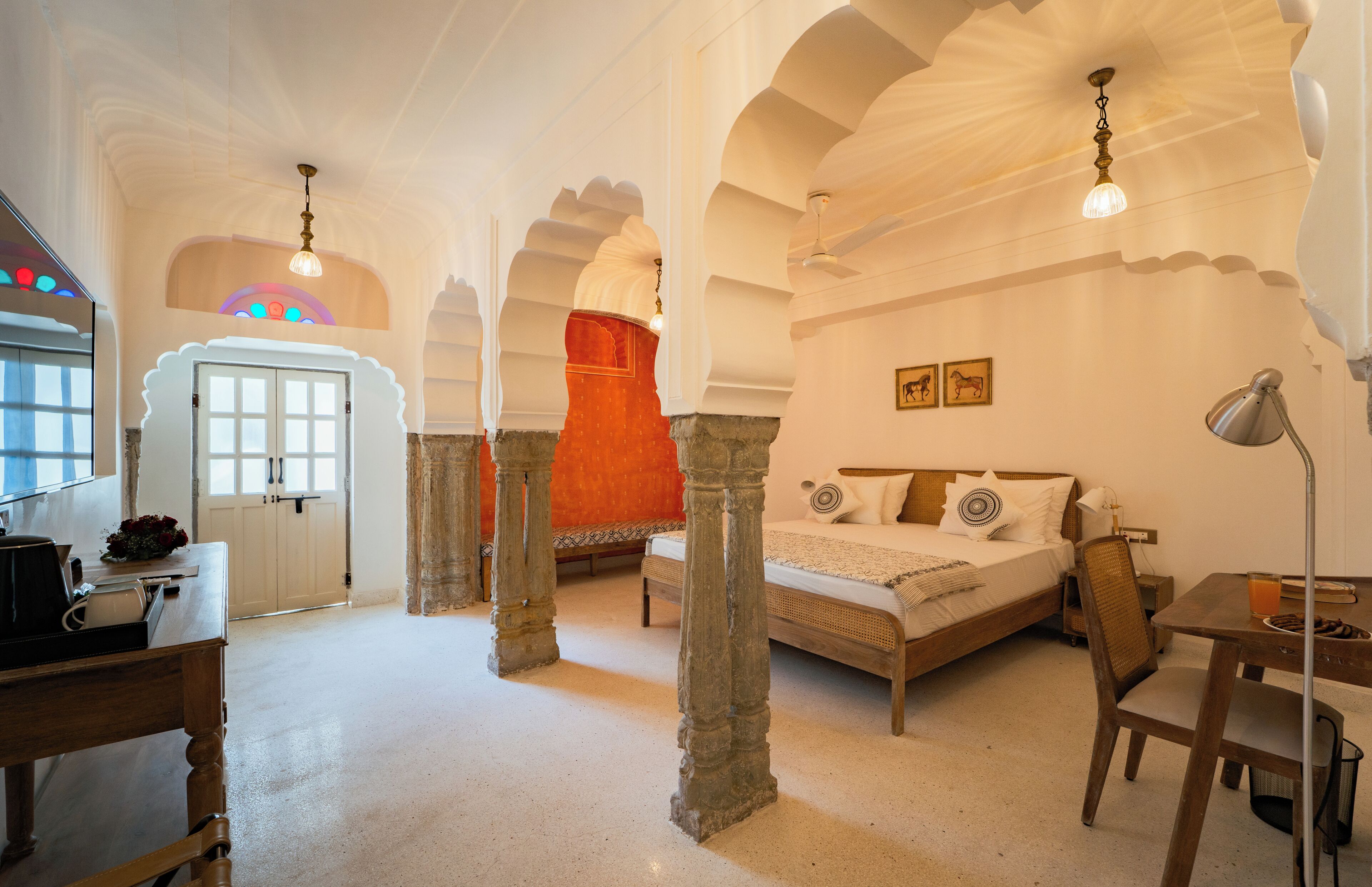 Una habitación con cama, escritorio, silla y puerta.