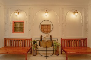 Une pièce comprenant deux bancs en bois, un miroir rond et des appliques murales décoratives.