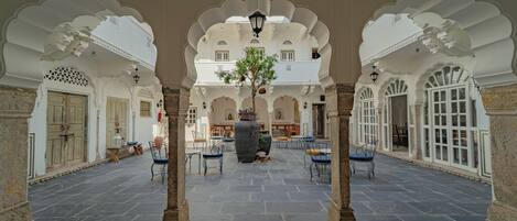 Un patio interior con suelo de piedra, arcos blancos y zonas de estar.