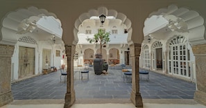 Un patio interior con suelo de piedra, arcos blancos y zonas de estar.