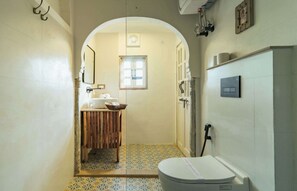 Un baño pequeño con inodoro blanco, lavamanos con tocador de madera y zona de ducha.