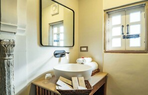 Un baño con un lavamanos grande de color blanco, un espejo y un ventanal con vistas.
