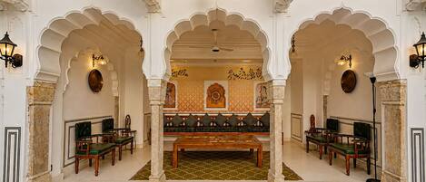 A traditional interior with a central seating area, ornate arches, and a patterned floor.
