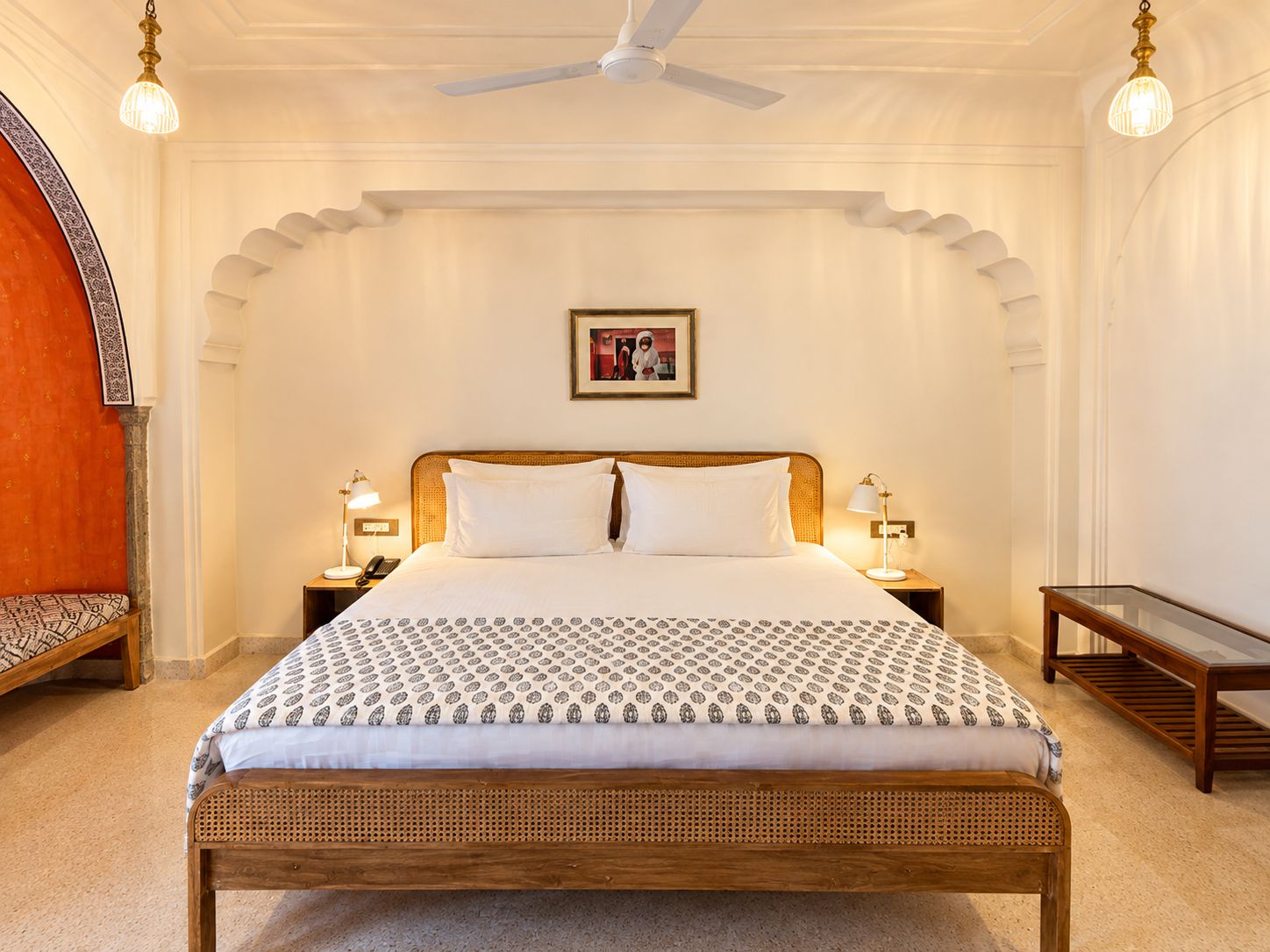 A hotel room with a large bed, two bedside tables, a ceiling fan, and a framed picture on the wall.
