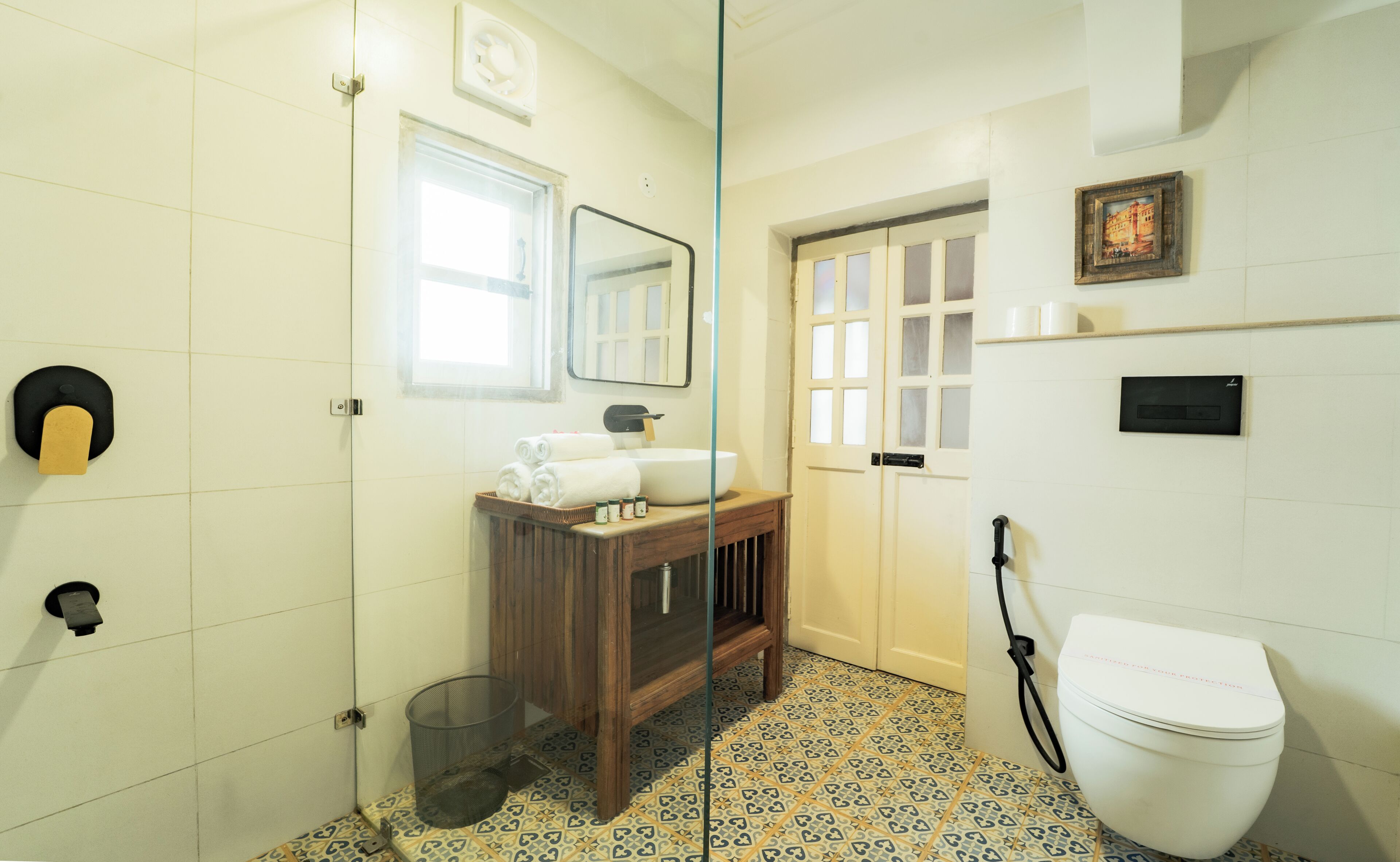 A bathroom with a white toilet, a sink, a mirror, and a window.