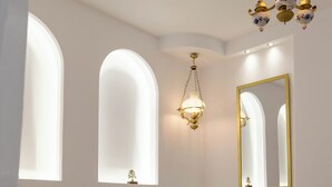 Una camera da letto con un letto, due finestre ad arco, uno specchio fissato alla parete e un lampadario.