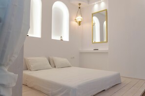 Ein Schlafzimmer mit einem Bett, einer Chandelier, einem Spiegel und einem Fenster.