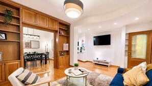 Un salon moderne comprenant un canapé, des fauteuils, une table basse et un téléviseur.
