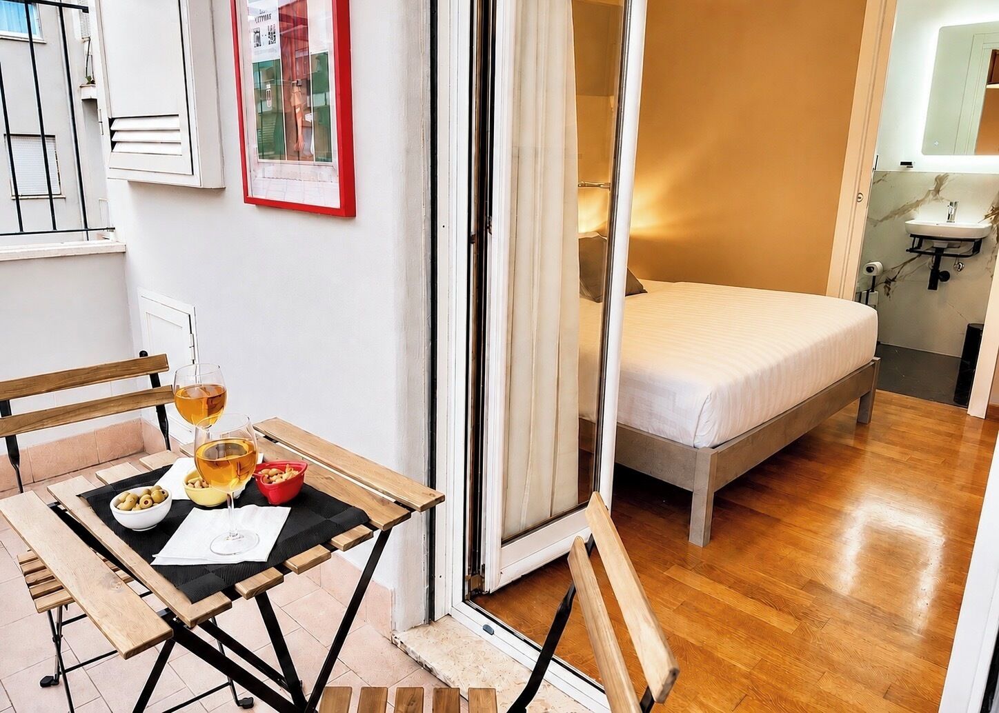 Un dormitorio con cama, un baño con lavamanos y una zona de comedor con mesa y sillas.