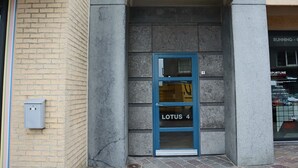 Een gebouwde ingang met een blauwe deur met de tekst 'LOTUS 4'.