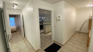 Een gang die leidt naar een slaapkamer met een bed, een kitchenette en een badkamer met een douche.