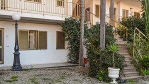 A building with a white facade, a staircase, and a garden area with a lamp post and a potted plant. - Lovely apartment in Ricadi with WiFi (Ricadi)