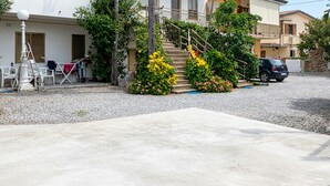A residential area with a concrete driveway, a staircase leading to a balcony, and a parked car. - Lovely apartment in Ricadi with WiFi (Ricadi)