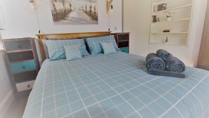A bedroom with a bed, a nightstand, a dresser, and a bookshelf. - Welcome Retreats (Plymouth)