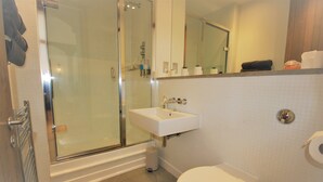 A bathroom with a glass-enclosed shower, a white sink, and a toilet. - Welcome Retreats (Plymouth)