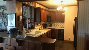 Une cuisine avec des meubles en bois foncé, un grand îlot central doté d’un évier et un réfrigérateur.