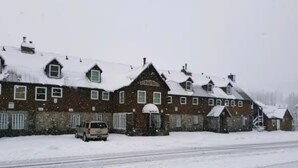 Un grand bâtiment en briques, doté de nombreuses cheminées et dont les toits sont recouverts de neige.