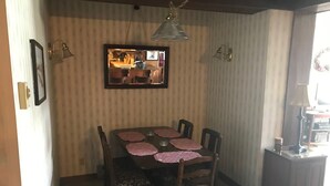 Un coin repas avec une table et des chaises en bois, un luminaire suspendu et un miroir au mur.