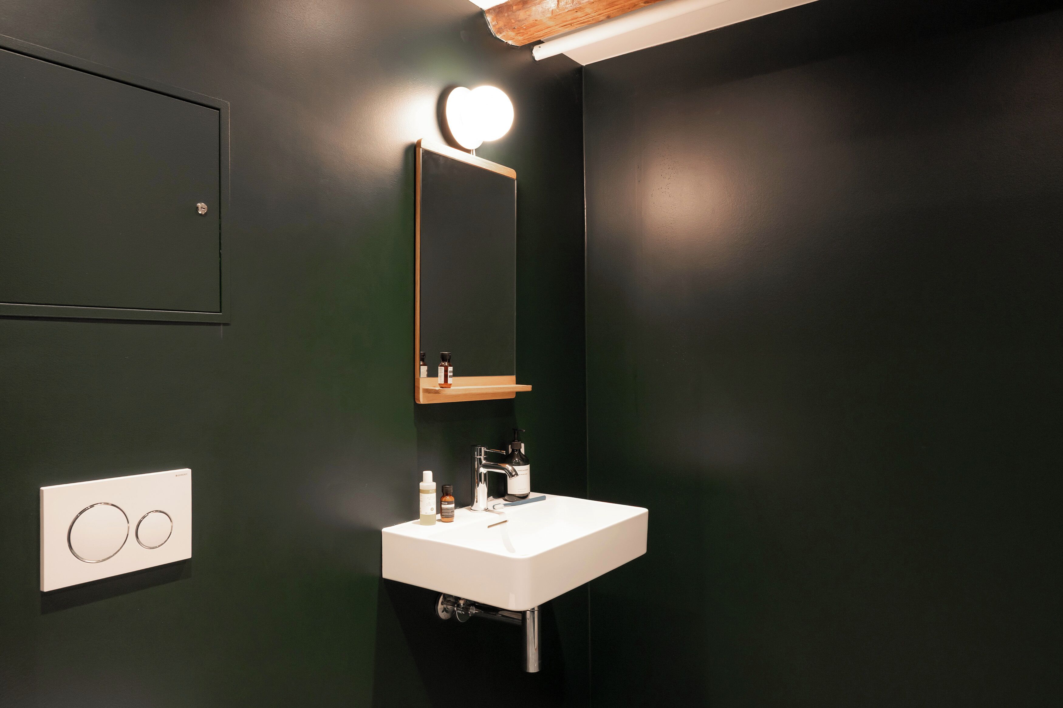 Een badkamer met een witte wastafel, een spiegel en een lamp boven de spiegel.