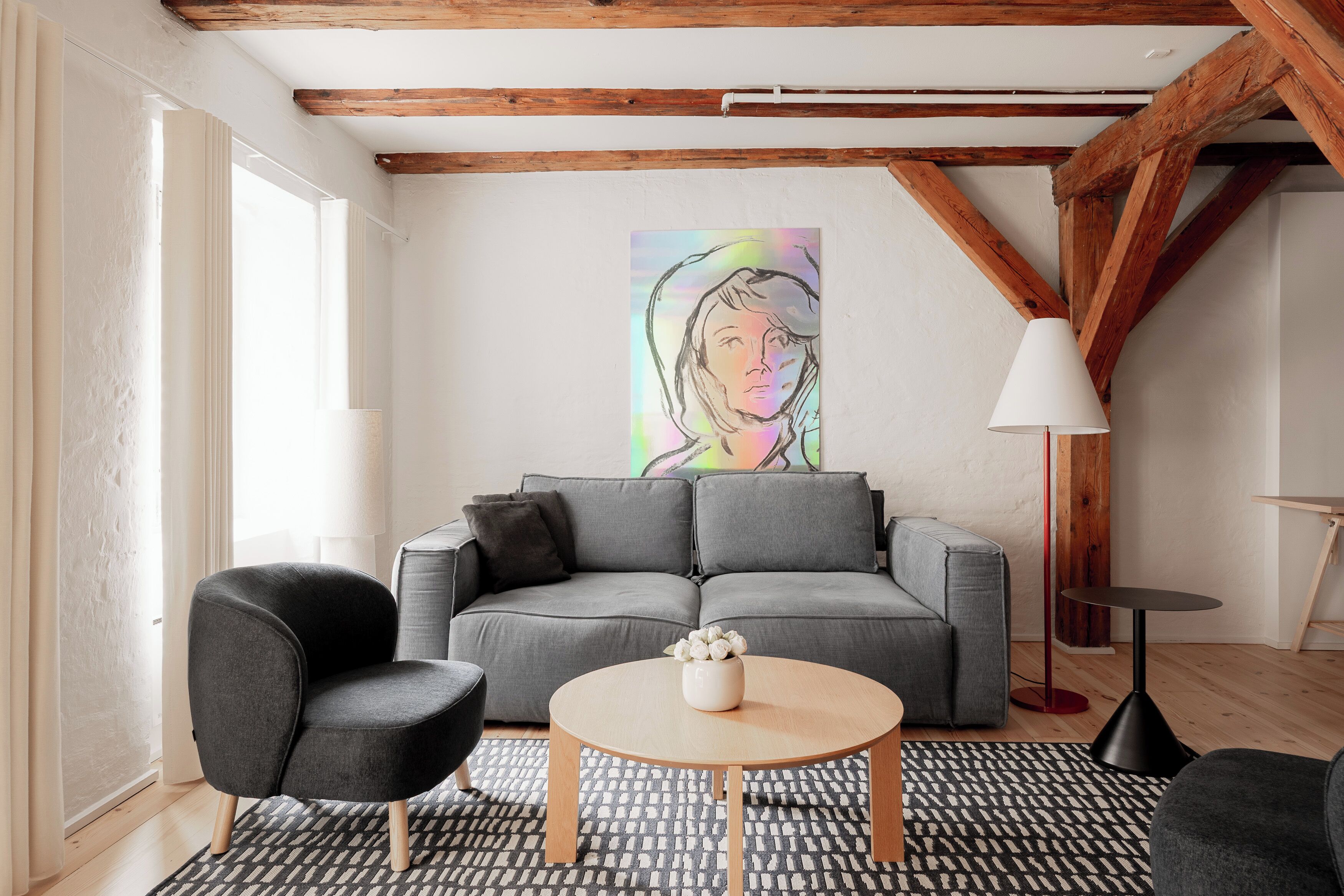 A modern living room with a grey sofa, a round coffee table, and a black armchair.