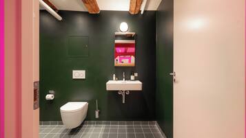 A bathroom with a white toilet, a sink with a mirror, and a green wall.