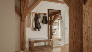 A room with wooden beams, a bench, and a coat rack with hats and bags. - Nyhavn43 Suites by Daniel&Jacob's (Copenhagen)