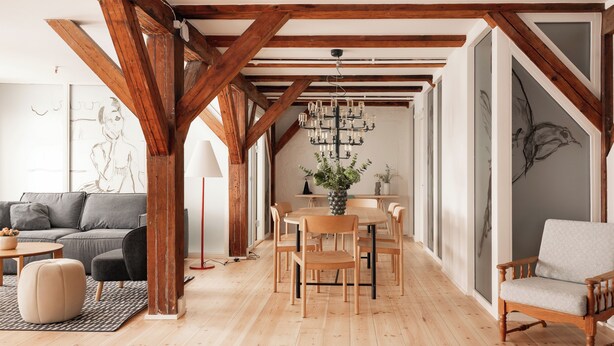 A spacious living area with wooden beams, a dining table with chairs, a sofa, and a coffee table. - Nyhavn43 Suites by Daniel&Jacob's (Copenhagen)