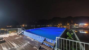 Een buitenzwembad, ligstoelen bij het zwembad