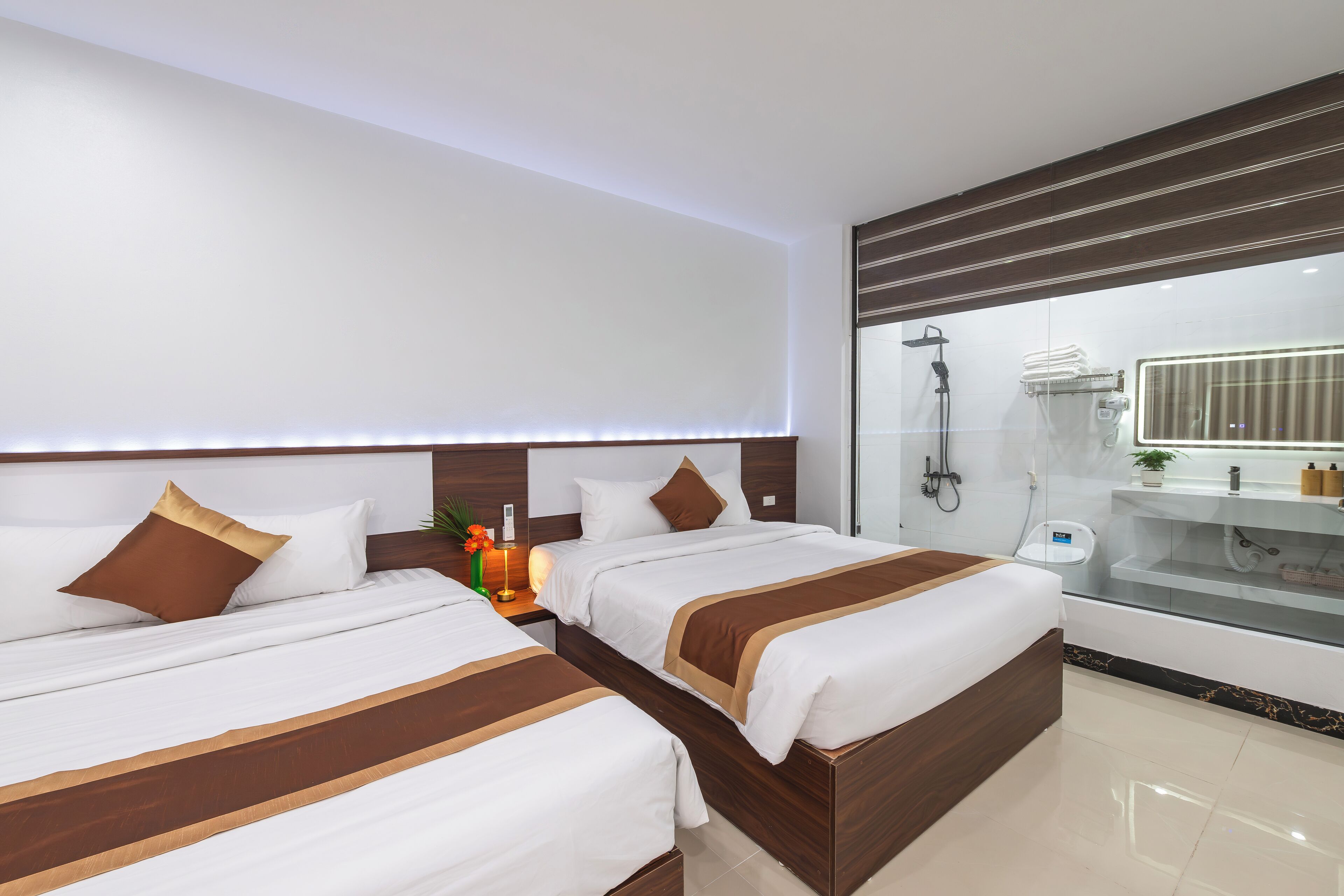 Una habitación de hotel moderna con dos camas, un espejo grande y una cabina de ducha de vidrio.