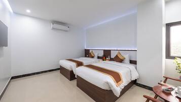 Een hotelkamer met twee bedden, een bureau, een stoel en een raam.