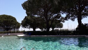 Ein Schwimmbecken mit klarem Wasser, Metallleiter und Liegestühlen.